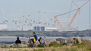 Des adolescents sont assis près du site de la centrale nucléaire de Hinkley Point en construction dans le Somerset, dans le sud-ouest de l'Angleterre, le 21 avril 2022.