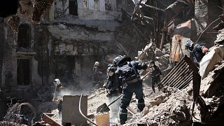 Donetsk People Republic Emergency Situations Ministry employees clear rubble at the side of the damaged Mariupol theater building during heavy fighting in Mariupol