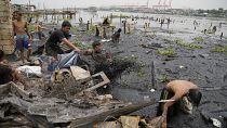 السكان وعمال النظافة يجمعون بقايا منازل محترقة بعد حريق دمر حيا فقيرا في محيط ميناء مانيلا في الفلبين. الجمعة 20 مايو 2022.