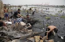 السكان وعمال النظافة يجمعون بقايا منازل محترقة بعد حريق دمر حيا فقيرا في محيط ميناء مانيلا في الفلبين. الجمعة 20 مايو 2022.