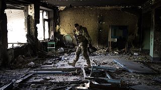 A Ukrainian serviceman inspects a school damaged during a battle between Russian and Ukrainian forces in the village of Vilkhivka near Kharkiv on 20 May 2022
