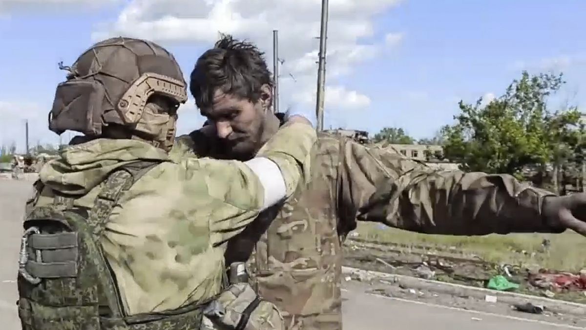 Orosz katona motoz egy, az Azovstalból távozó ukrán katonát 2022. május 20-án