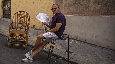 A man cools himself with a fan in the Rastro flea market during a heatwave in Madrid in August 2021