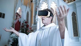 L'image est une photo composite montrant un prêtre portant un casque de RV. Les églises se tournent vers le Métavers pour faire connaître la liturgie à un public numérique.