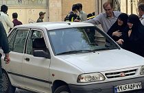family members of Col. Hassan Sayyad Khodaei weep over his body at his car after being shot by two assailants in Tehran, Iran, Sunday, May 22, 2022.