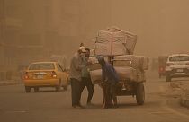 People push a cart during a sandstorm in Baghdad