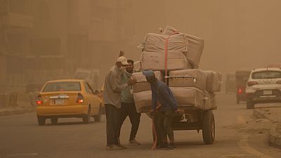 People push a cart during a sandstorm in Baghdad