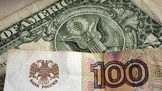 تم تصوير ورقة نقدية من فئة مائة روبل أمام ورقة ورقية بالدولار الأمريكي، غيلسنكيرشن، ألمانيا، الاثنين 25 أبريل 2022