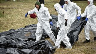 Tömegsírból kihantolt emberek nejlonzsákba helyezett holttesteit fektetik egymás mellé Bucsában