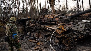 A Ukrainian soldier stands one top of a destroyed Russian tank on the outskirts of Kyiv, Ukraine, Thursday, March 31, 2022.