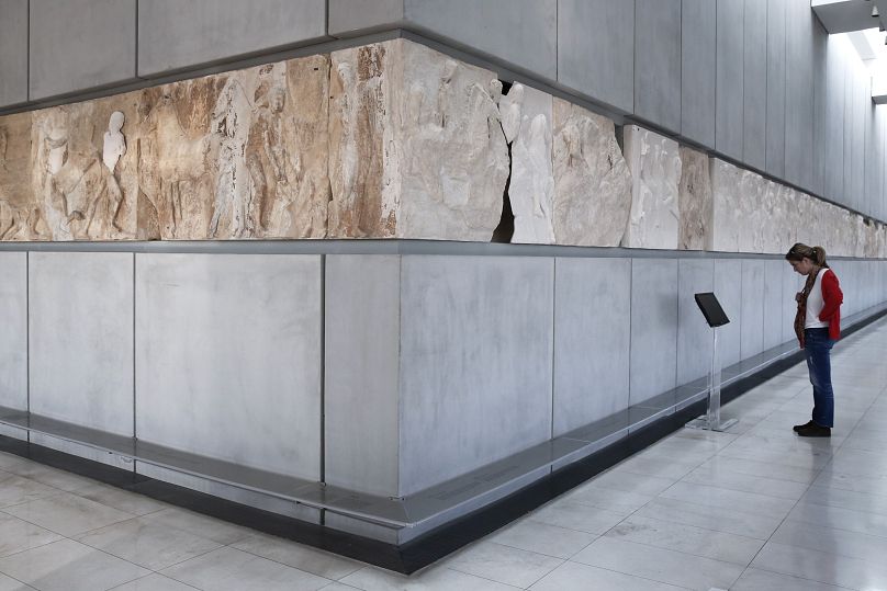 A visitor to Athens' Acropolis Museum looks at the frieze of the Temple of Parthenon, the white parts representing the frieze segments displayed at London's British Museum