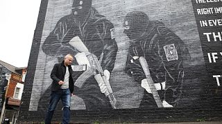 Loyalist activist Jamie Bryson walks past a Ulster Volunteer Force mural in east Belfast, Northern Ireland, Oct. 15, 2019.