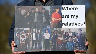 أحد أفراد عائلات الإيغور يحمل لافتة لأقاربه المعتقلين في الصين أثناء مظاهرة.