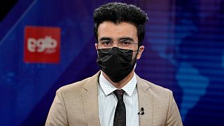 مجری مرد شبکه طلوع نیوز افغانستان که به نشانه همبستگی با همکاران زن خود ماسک به صورت زده است