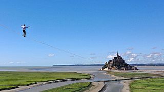 French tightrope walker Nathan Paulin walking on a slackline in the bay of Le Mont Saint-Michel