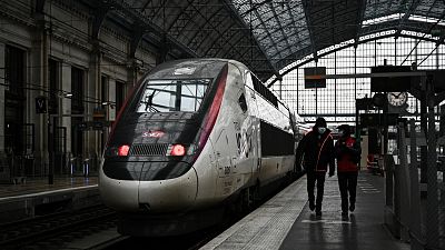 SNCF personnel members walk past a TGV (high speed train) at the railway station in Bordeaux, southwestern France.