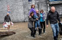 A woman is carried through a flooded street in Belgium, scenes which are likely to be more frequent in the future due to climate change