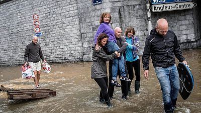 A woman is carried through a flooded street in Belgium, scenes which are likely to be more frequent in the future due to climate change