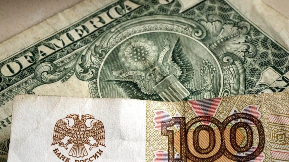 ورقة نقدية من فئة مائة روبل أمام ورقة ورقية بالدولار الأمريكي