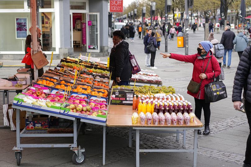 People choose fruits and vegetables to buy in a street market in Berlin, April 2022