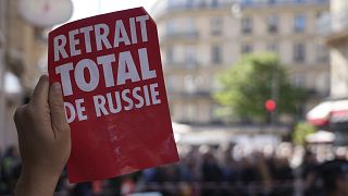 An environmental activist holds a poster reading "Total Withdrawal from Russia"