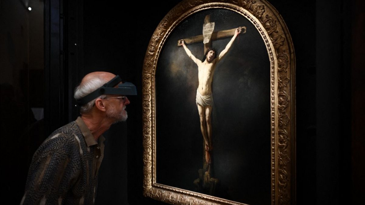 A French painting restorer inspects a 1631 oil on canvas painting by Rembrandt, "The Christ on the Cross" 