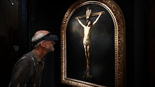 A French painting restorer inspects a 1631 oil on canvas painting by Rembrandt, "The Christ on the Cross"