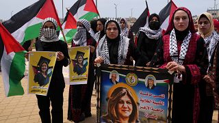 Estudiantes ondean sus banderas nacionales y portan fotos de la periodista asesinada de Al Jazeera, Shireen Abu Akleh, el 16 de mayo de 2022.