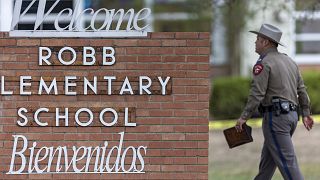 Un policier passe devant le panneau de l'école primaire Robb à Uvalde, au Texas, le mardi 24 mai 2022.