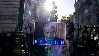 متظاهر يحمل لافتة تطالب رئيس الوزراء البريطاني بالاستقالة