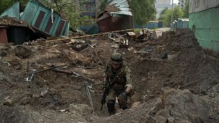 A special task force policeman inspects a site after an airstrike by Russian forces in Lysychansk on 13 May 2022