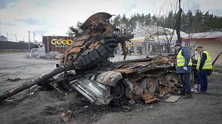 Road workers examine a destroyed Russian tank on the highway to Kyiv on 11 April 2022