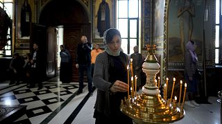 A woman lights a candle at Kyiv Pechersk Lavra Monastery in Kyiv on 28 May 2022