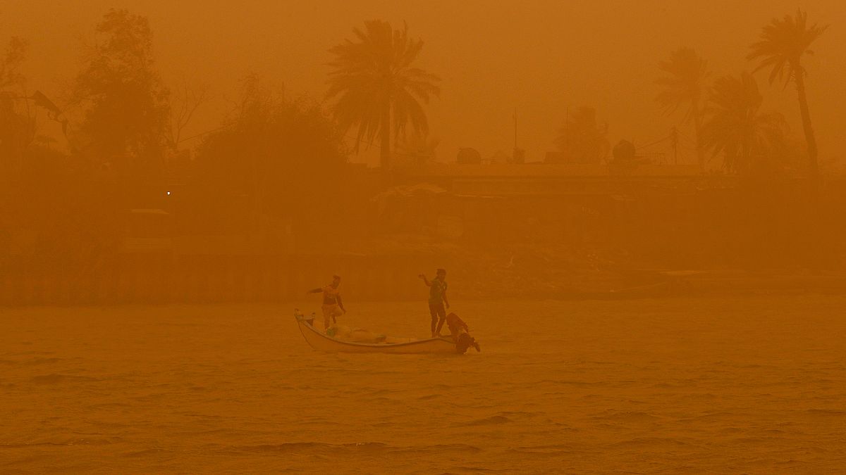 صيادون يبحرون في مجرى شط العرب المائي خلال عاصفة رملية في البصرة - العراق. 2022/05/23