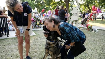 A woman gives a hug to a dog around a temporary memorial set up for victims of shooting in Uvalde, Texas.