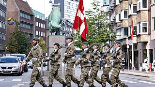 Soldados marchan mientras llevan la bandera danesa