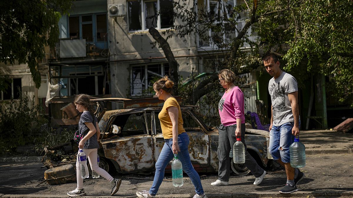 Славянск. Жители города несут воду в укрытия мимо здания, пострадавшего от ракетного удара