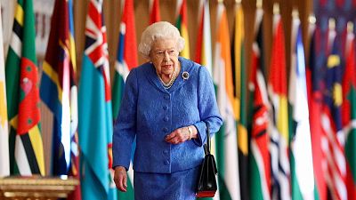 FILE - Britain's Queen Elizabeth II walks past Commonwealth flags in St George's Hall at Windsor Castle, 6 March 2021