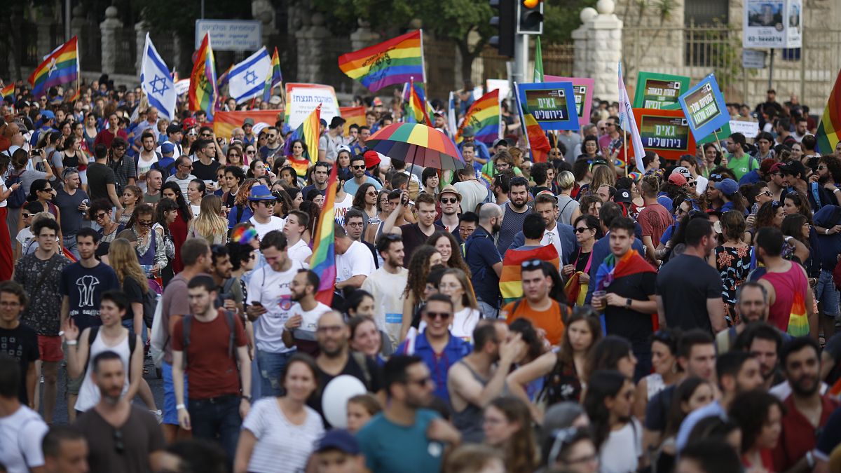 إسرائيليون يلوحون بالأعلام ويحملون لافتات خلال موكب المثليين السنوي في القدس. 2019/06/06