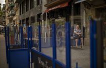 Eine Frau sitzt auf einem Tisch vor einer geschlossenen Bar während der Pandemie in Barcelona, 01.06.2020