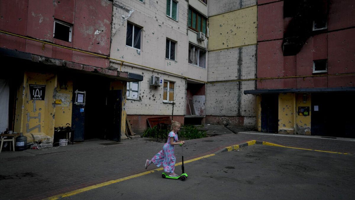 Девочка на самокате среди разрушенных войной зданий в Укриане