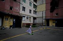 Девочка на самокате среди разрушенных войной зданий в Укриане