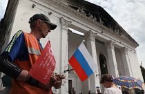 Un hombre con una bandera rusa en el centro de Mariúpol