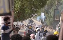 Riot police firing tear gas bombs towards protestors, protestors throwing back tear gas bombs towards police in Khartoum, Sudan.