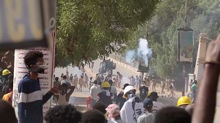 Riot police firing tear gas bombs towards protestors, protestors throwing back tear gas bombs towards police in Khartoum, Sudan.