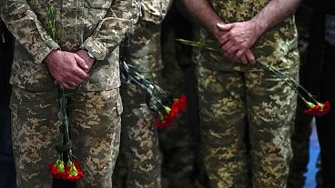Ukrainian servicemen hold flowers during a funeral service for Army Col. Oleksander Makhachek in Zhytomyr on 3 May 2022