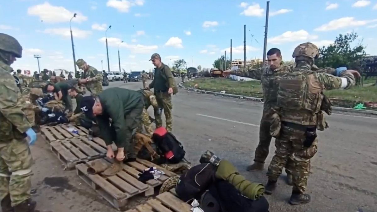 Orosz katonák vizsgálják át az ukrán katonákat, akik megadták magukat az Azovstal erőműben 2022. május 20-án