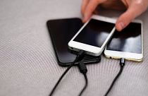 Phones are shown charging. The EU initiative would create a common charger.