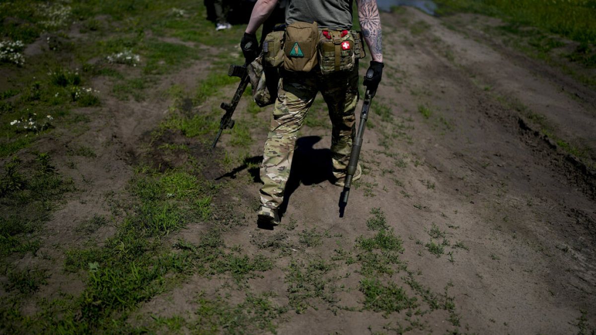 Un miliciano civil sostiene una escopeta y un rifle durante un entrenamiento en un campo de tiro en las afueras de Kiev, Ucrania, el martes 7 de junio de 2022