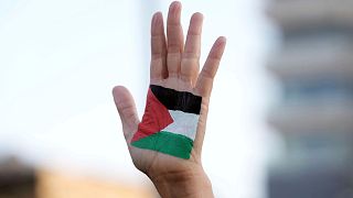 پرچم فلسطین که بر دست یک ساکن سرزمین‌های فلسطینی نقش بسته
